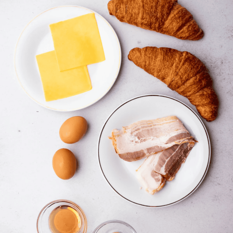 Ingredients for an air fryer bacon egg and cheese croissant: croissants, bacon, eggs, cheese, and brown sugar.