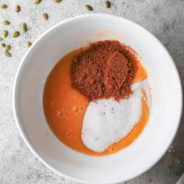 Flour, cinnamon, and pumpkin pie spice whisked together in a white mixing bowl