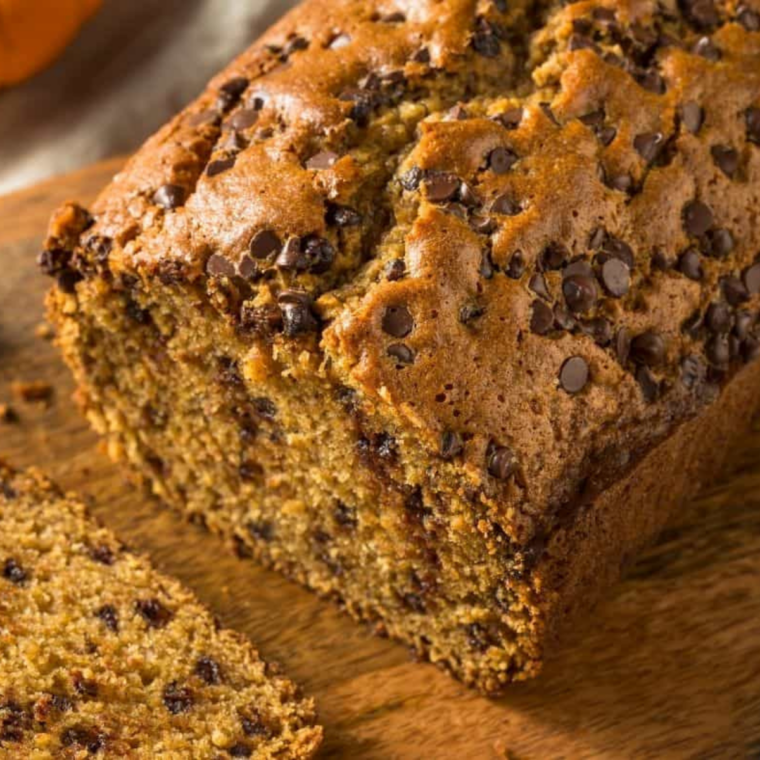 A slice of pumpkin bread on a plate beside a cup of coffee