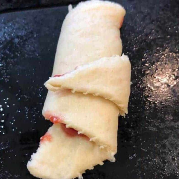 Filled crescent rolls arranged in an air fryer basket, ready to cook at 320°F.