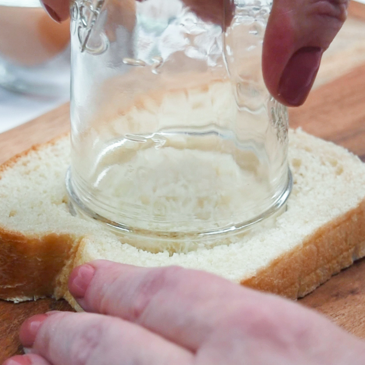 Buttered slice of bread with a round hole cut in the center for egg in a hole
