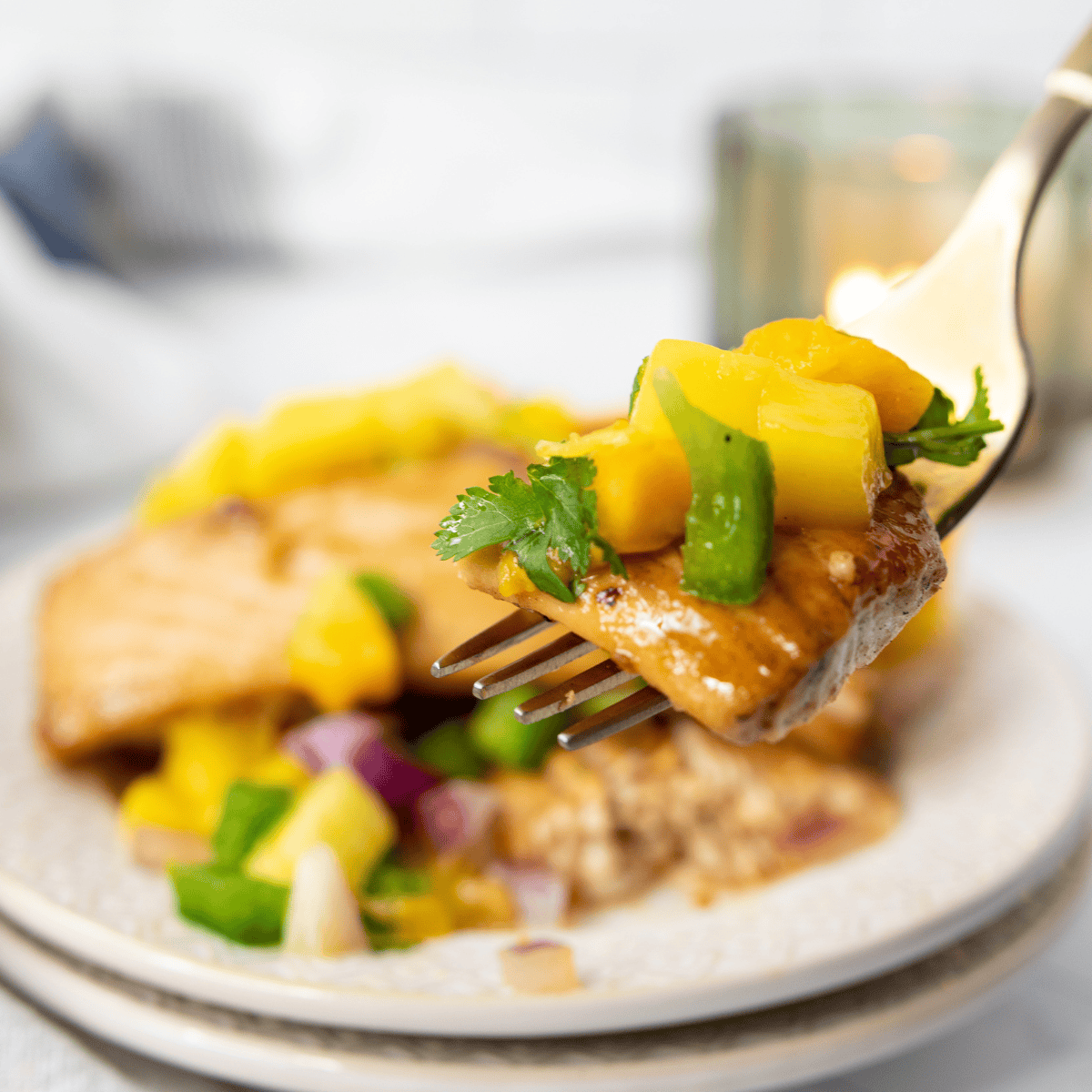 Air fryer cooked swordfish steak topped with fresh mango salsa and garnished with herbs.
