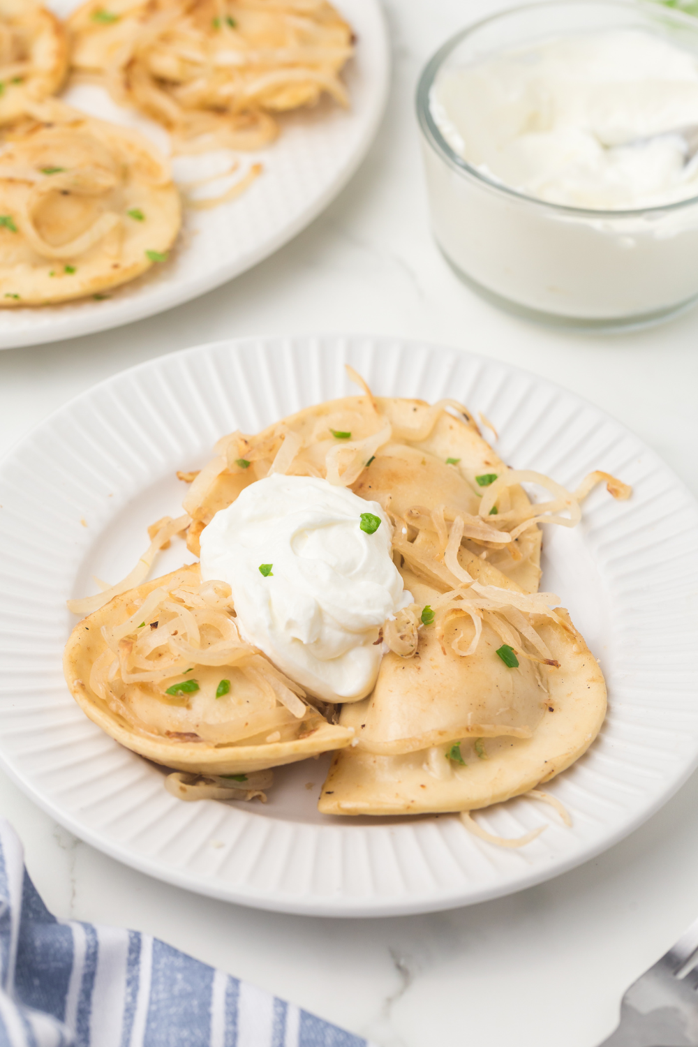 Golden-brown air fryer pierogies served with caramelized onions and sautéed peppers on a plate.