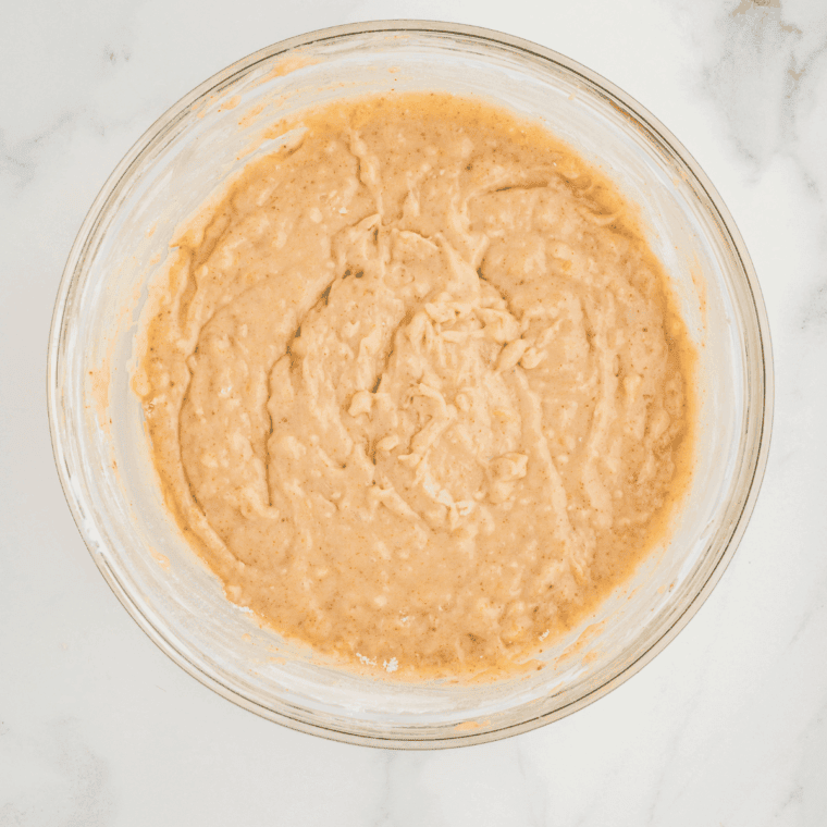 Whisking together flour, baking soda, and salt, then gently folding dry ingredients into banana mixture to create tender banana bread batter.