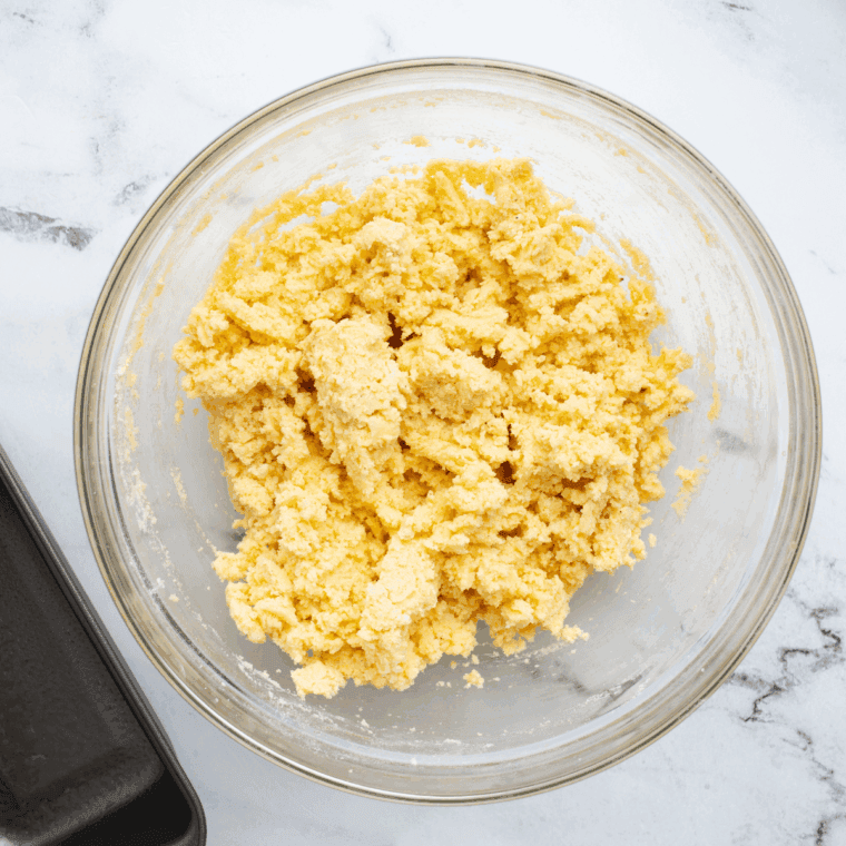 Combining wet and dry ingredients to form a thick, sticky lemon protein bar dough.