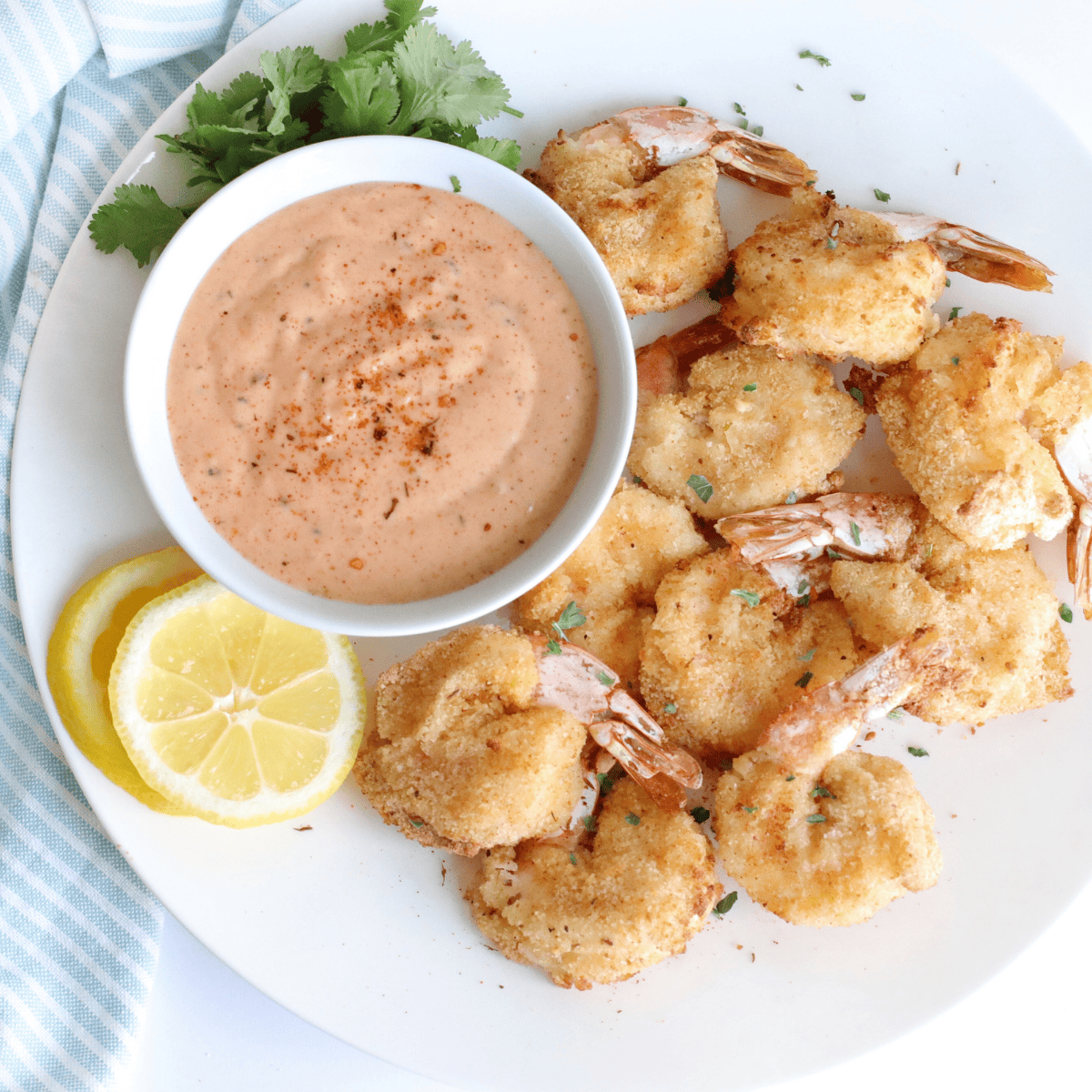 Golden crispy copycat Long John Silver's battered shrimp piled in a parchment-lined bowl with lemon wedge and cocktail sauce