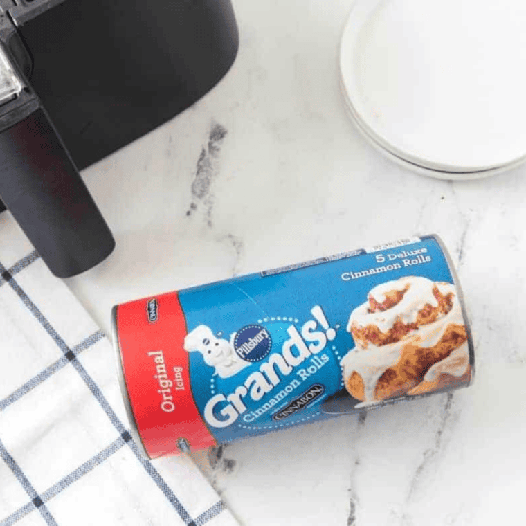 Can of refrigerated cinnamon rolls, peach pie filling, and diced pecans on a counter