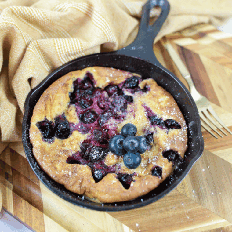Golden blueberry Dutch baby pancake fresh from the air fryer, topped with fresh blueberries