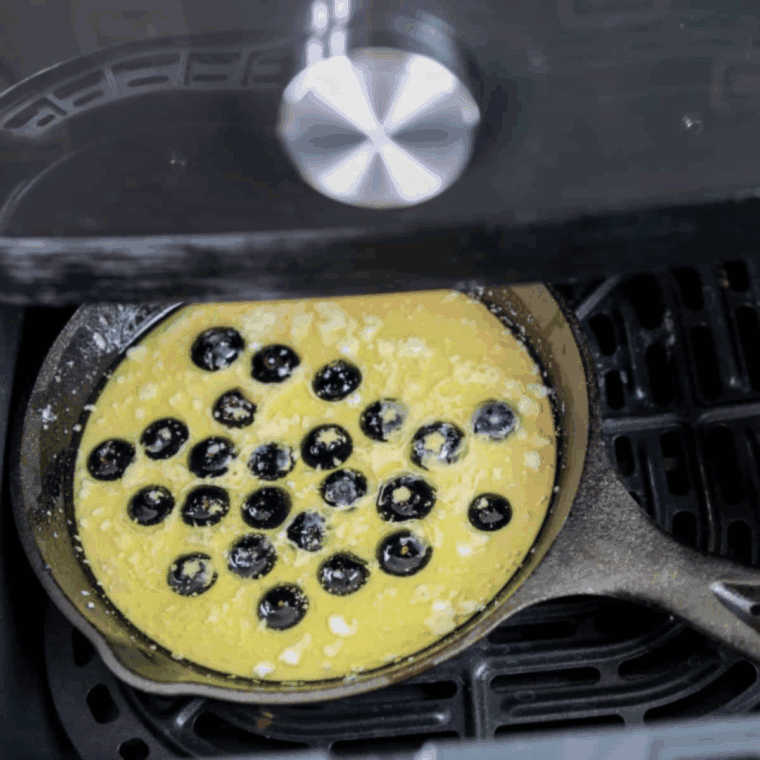 Pouring pancake batter into greased skillet, adding blueberries, air frying until golden and berries burst