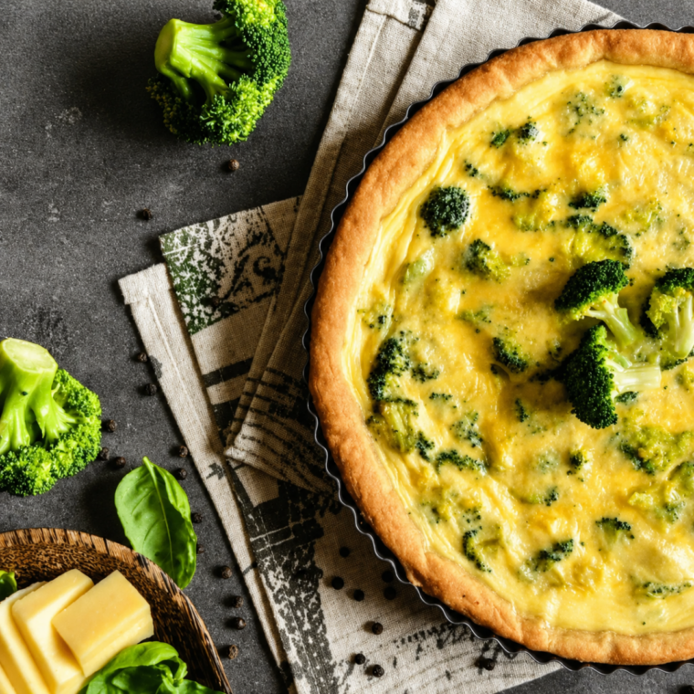 Baked broccoli cheddar quiche resting on a cooling rack before slicing