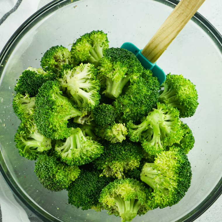 Broccoli florets, shredded cheddar and beaten eggs being whisked together in a glass bowl