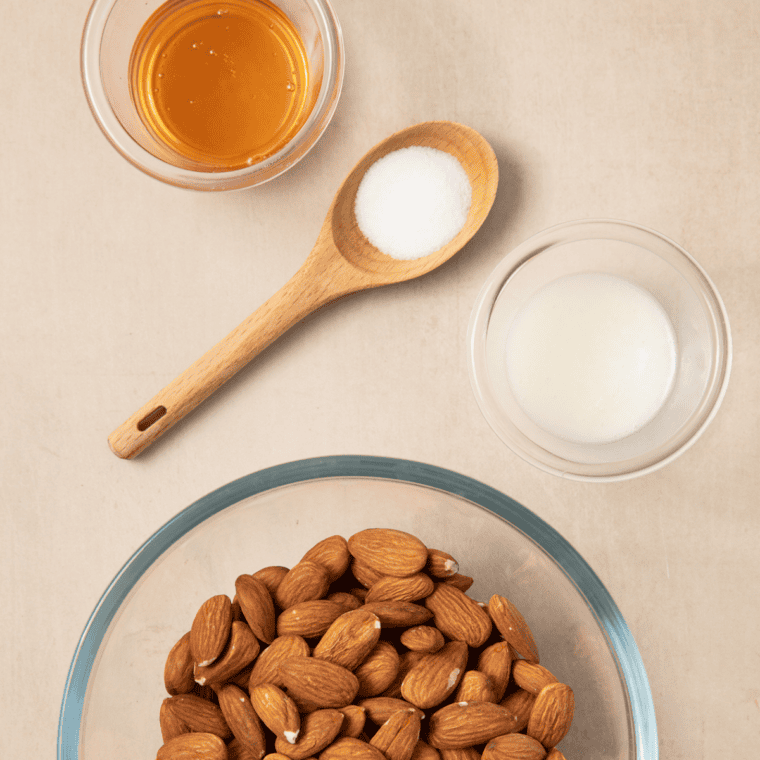 Raw almonds, sugar, brown sugar, cinnamon, egg white, and vanilla measured out for candied almonds