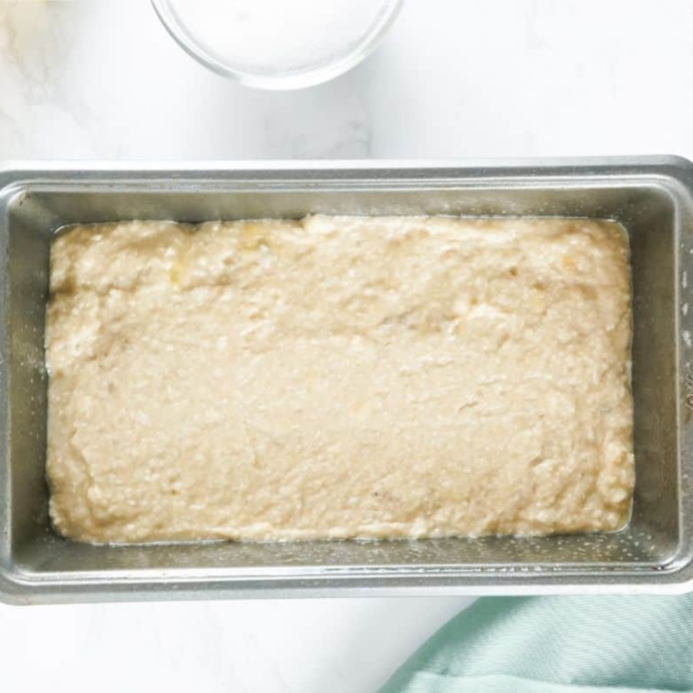 Gluten-free banana bread batter poured into a greased mini loaf pan