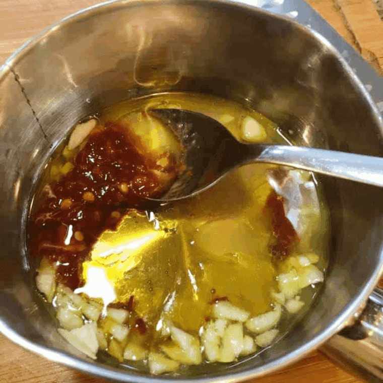 Small saucepan with olive oil and minced garlic simmering for pork chop sauce.