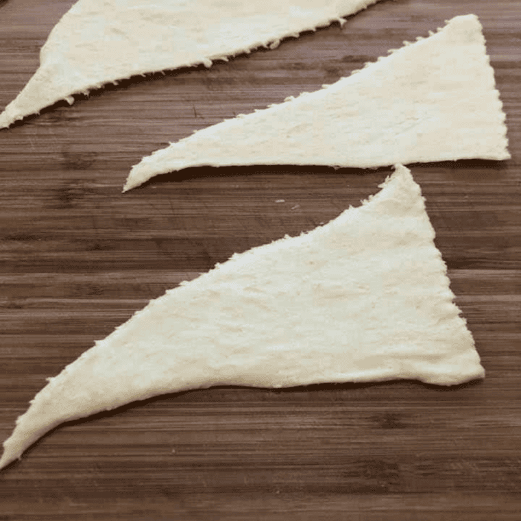 Crescent roll dough separated into eight triangles on a cutting board