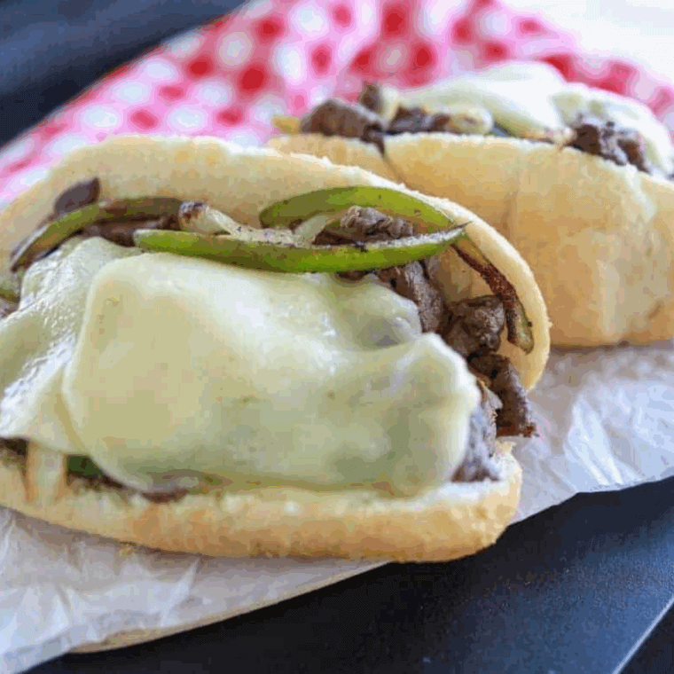 Juicy Ninja Foodi Philly cheesesteak sandwich filled with sliced beef, peppers, onions, and melted cheese on a toasted hoagie roll.