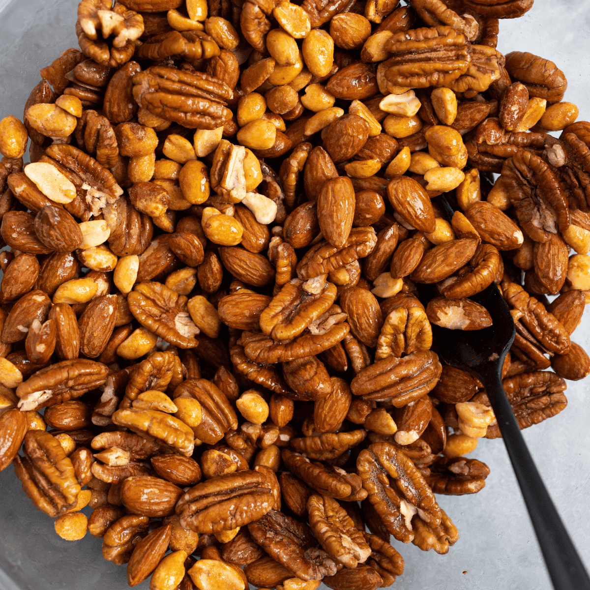 Raw mixed nuts in a glass mixing bowl before seasoning