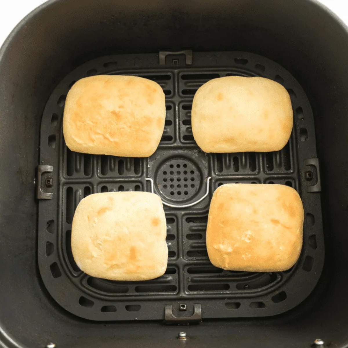 Frozen Sister Schubert's rolls arranged in a single layer in an air fryer basket with space between each one