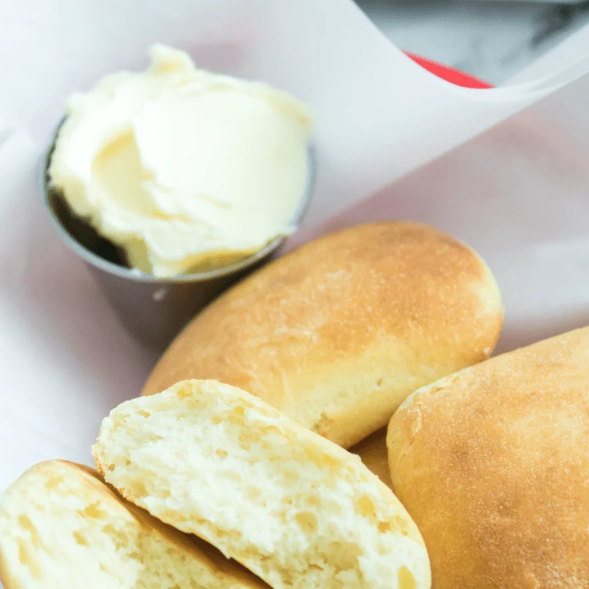 Golden Sister Schubert's dinner rolls in an air fryer basket brushed with melted butter
