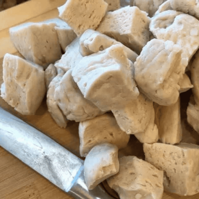 Refrigerated buttermilk biscuit dough cut into 1-inch pieces with kitchen shears on a cutting board
