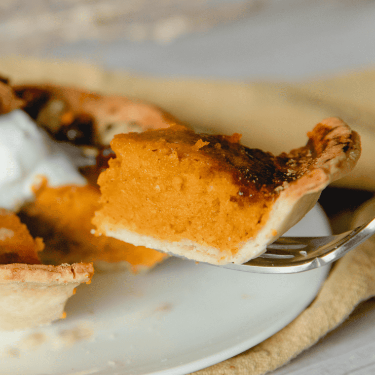 Finished air fryer pumpkin pie on a plate topped with whipped cream