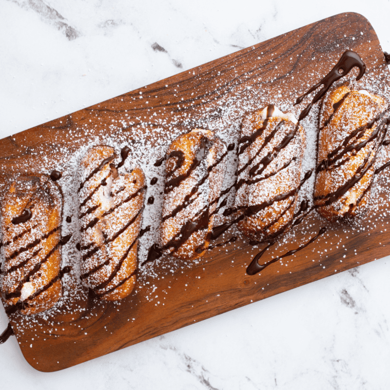 Air Fryer Twinkie Variations Air-fried Twinkies are already a fun twist on the classic treat, but you can take things to the next level with these creative variations: Chocolate-Dipped: Dip the Twinkies in melted chocolate after air frying and let them set. This adds an extra layer of richness. Twinkie S'mores: Once air-fried, slit the Twinkie in the middle and stuff with a piece of chocolate and a roasted marshmallow. Press together and enjoy! Nut-Crusted: Before air frying, dip the Twinkie in batter and roll in crushed almonds, pecans, or your nut of choice. Drizzles: After air frying, drizzle of raspberry sauce, Hershey's Chocolate Syrup, or a drizzle of chocolate sauce. Stuffed Twinkies: Before air frying, use a piping bag to add fillings, such as fruit jams, Nutella, or peanut butter, to the creamy vanilla filling. Fruit-Topped: After air frying, serve the Twinkies topped with fresh berries or a dollop of whipped cream. Batter Variations: Play with batter flavors—use cocoa powder for a chocolatey crust or add cinnamon and sugar for a churro-like taste. Wrapped Twinkies: You can wrap the Twinkie with crescent dough Twinkie Sliders: Slice air-fried Twinkies in half and add a scoop of ice cream in between for a delightful dessert slider. Remember, the sky's the limit! Feel free to get creative and mix and match different variations for a truly unique treat. Pro Tips For The Perfect Air Fryer Twinkie When aiming for the perfectly golden and delicious air-fried Twinkie, consider these pro tips: Preheat the Air Fryer: Always preheat your air fryer. This ensures even cooking right from the start. No Overcrowding: Make sure the Twinkies are not touching each other in the air fryer. Overcrowding can prevent them from crisping up uniformly; depending on the size of your air fryer, you can probably fit 6-8 Twinkies in the air fryer basket. Flip or Rotate: Halfway through the cooking time, gently flip or rotate the Twinkies to ensure an even golden color on all sides. Watch the Clock: Twinkies can go from golden to burnt quickly. Keep a close eye, especially when making them in your specific air fryer. Use Non-Stick Spray: If you're worried about sticking, lightly spray your air fryer basket with non-stick cooking spray or parchment paper. Cooldown Time: After removing from the air fryer, let them cool for a minute or two. This allows the exterior to crisp up further while not scalding your mouth when you bite. Presentation Matters: Lightly dusting powdered sugar or a drizzle of your favorite sauce can elevate your air-fried Twinkies' visual appeal and taste. Experiment with Batter: If you're using batter, try different varieties to find your preferred texture and flavor. Thicker batter will give a more doughnut-like crust, while thinner batter provides a light crispiness. With these tips, you'll be on your way to creating perfect air-fried Twinkies every time! Do I need to defrost the Twinkies before air frying? No, you can air fry them straight from the freezer, especially if they're pre-packaged. However, the cooking time may vary slightly based on their temperature. Can I make my Twinkies instead of using store-bought? Absolutely! If you have a favorite homemade Twinkie recipe, you can certainly use that. Just ensure they're fully assembled before air frying. How long do air-fried Twinkies stay fresh? Air-fried Twinkies are best enjoyed immediately while they're warm and crispy. However, if you have leftovers, store them in an airtight container and consume them within 1-2 days for the best taste and texture. Is air frying healthier than deep frying? Generally, yes. Air frying requires significantly less oil than traditional deep frying, which reduces the overall fat content. Can I use other fillings or different flavors of Twinkies? Yes! Feel free to experiment with different Twinkie varieties or flavors available in the market. How do I know when the Twinkies are done in the air fryer? They should have a golden-brown exterior. However, since air fryer models can vary, always keep an eye on them during the first batch to nail the perfect cooking time. Can I reheat leftover air-fried Twinkies? Yes, you can reheat them in the air fryer at 350°F for 1-2 minutes or until they're warm throughout. Is it necessary to use batter when air frying Twinkies? No, using pancake mix or batter is optional. Using batter will give them a crispy crust, but they can be air-fried without batter, too.