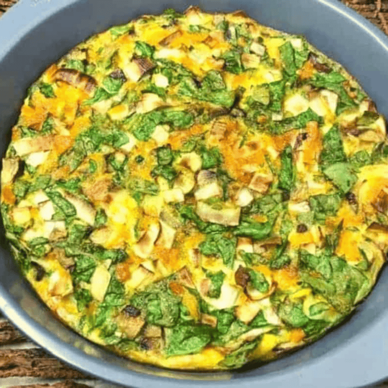 Roasted vegetable frittata sliced on a plate showing fluffy eggs and colorful roasted vegetables inside.