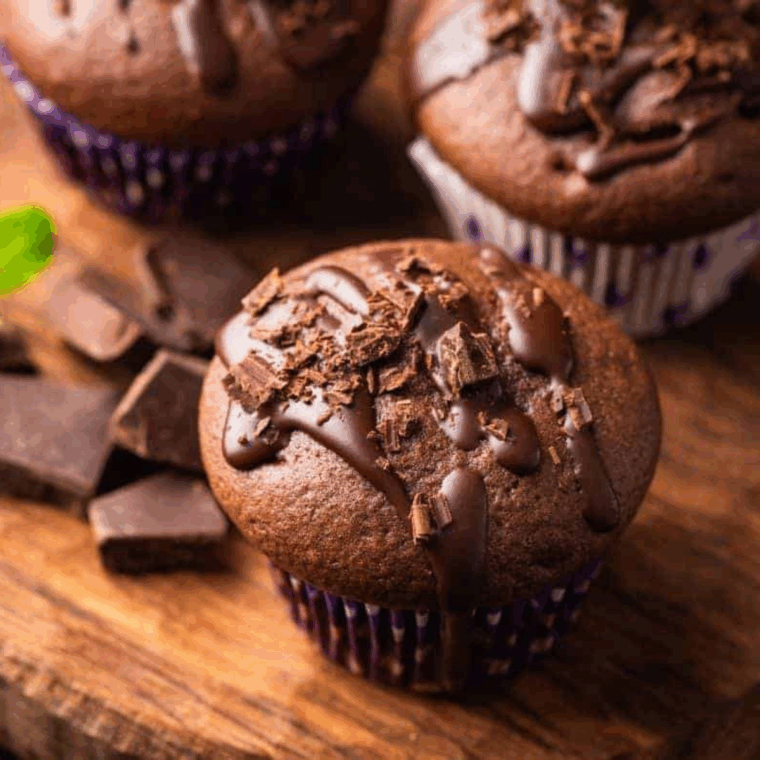 Close-up of a Copycat Costco Double Chocolate Muffin with chocolate chips, golden brown and moist, on a white plate.