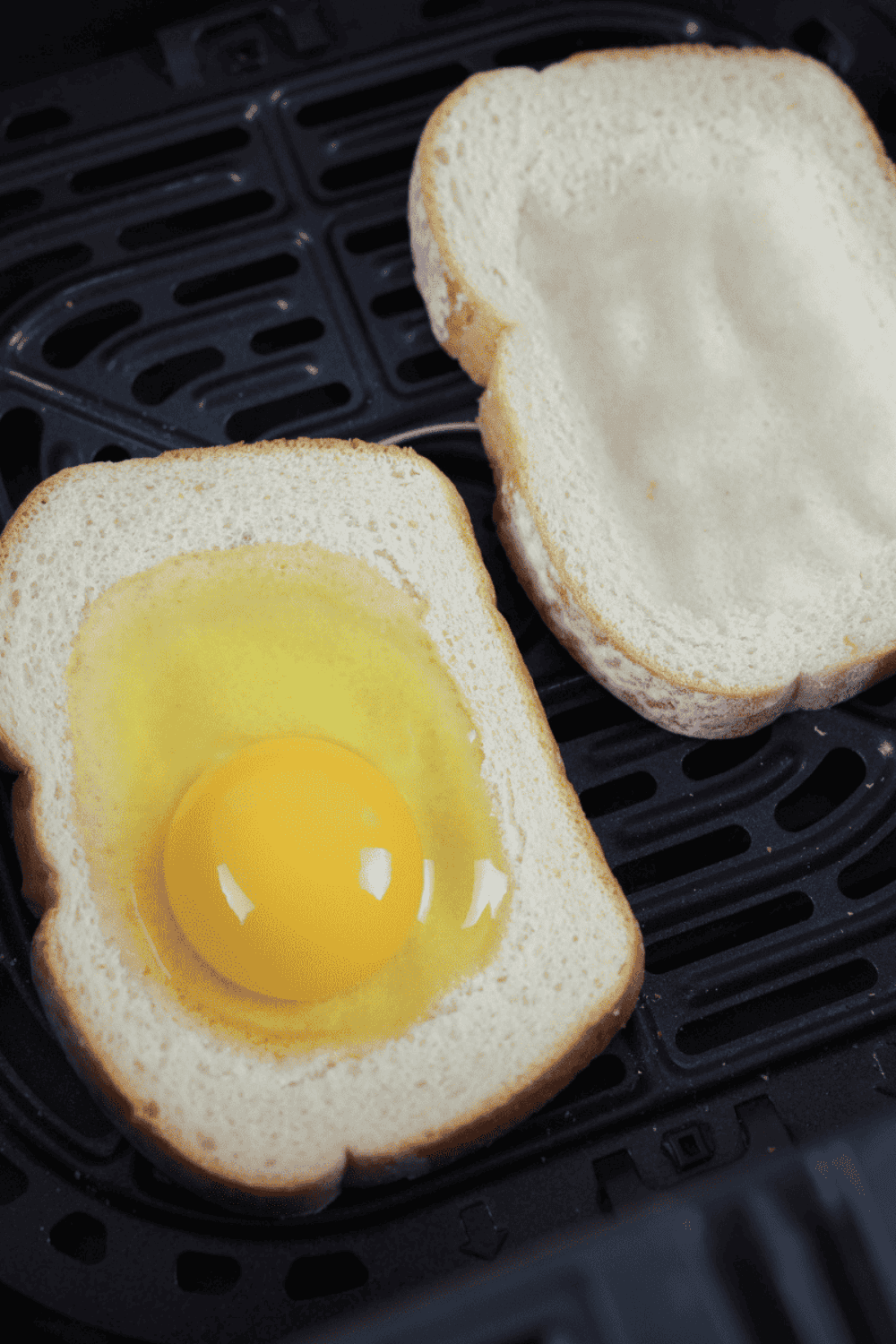 Egg cracked into the center of hollowed bread slice, ready to cook in the air fryer for 3–5 minutes.