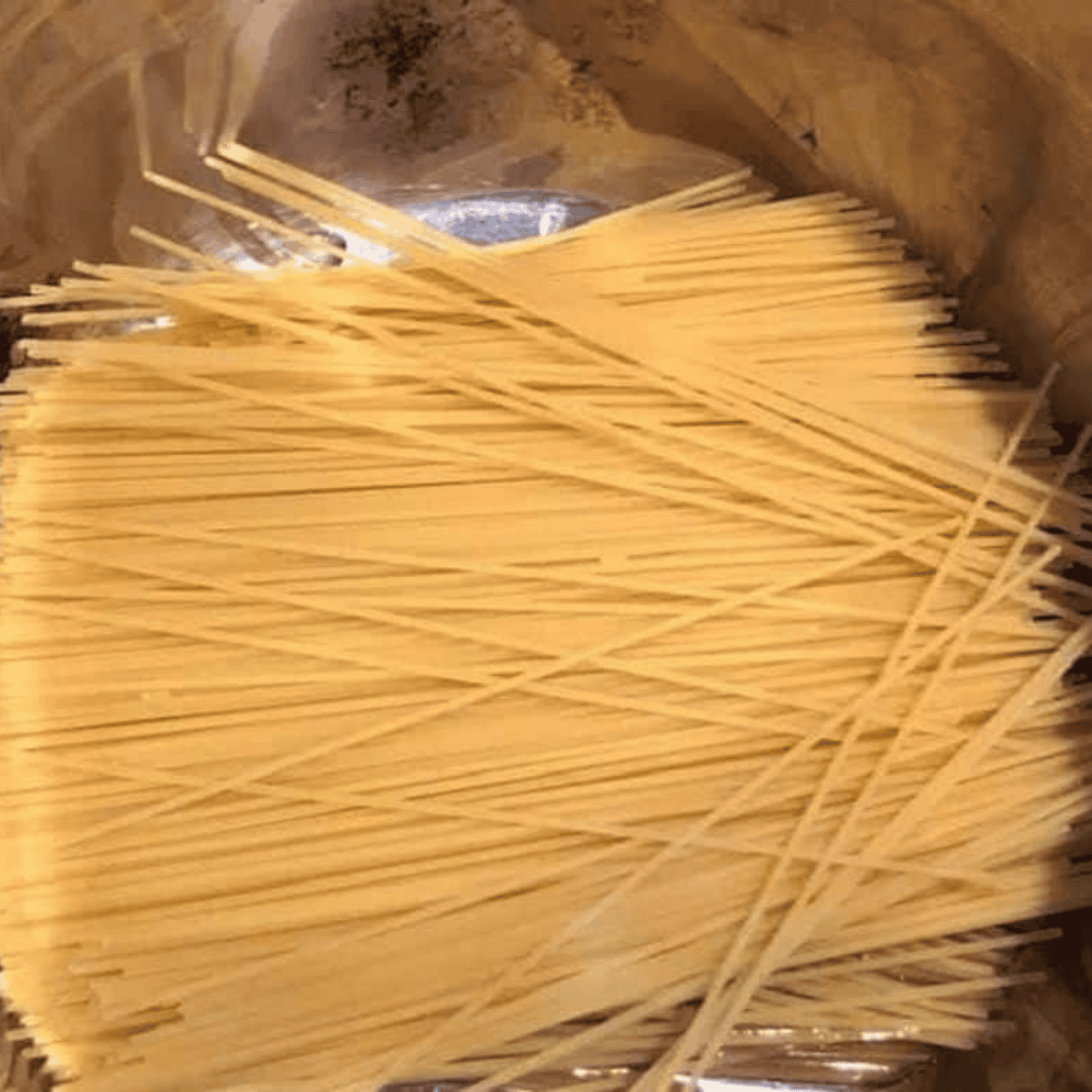 Broken thin spaghetti layered in a criss-cross pattern inside the Instant Pot to prevent clumping during pressure cooking.