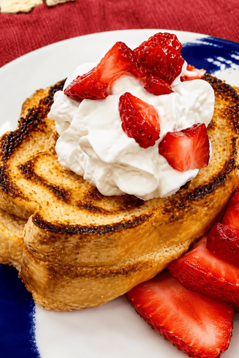 Air fryer strawberry shortcake French toast on a plate topped with whipped cream and sliced strawberries