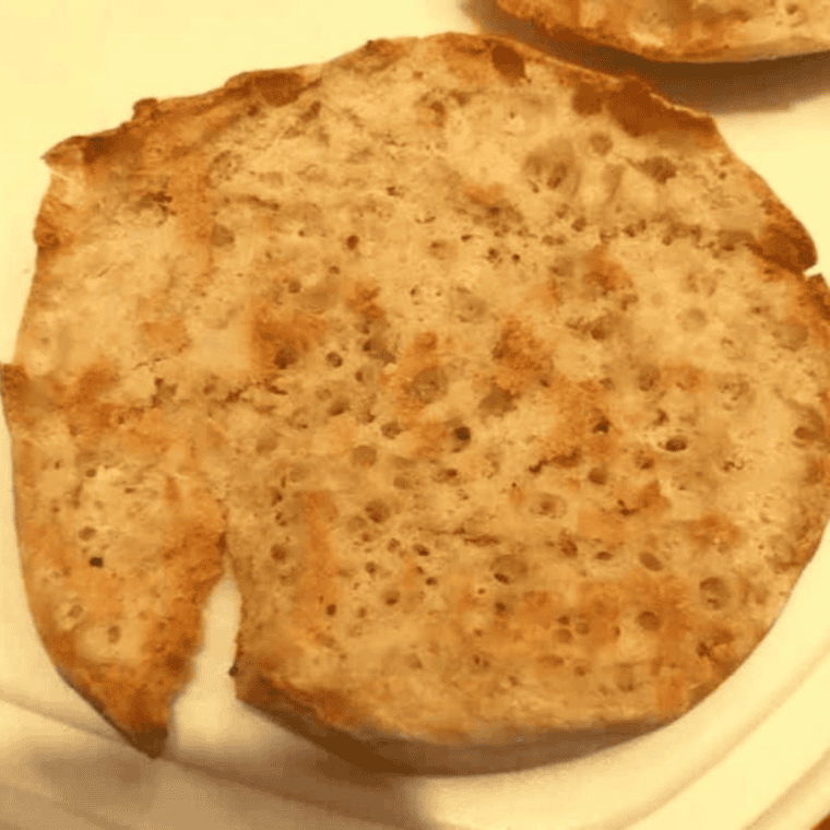 English muffin halves in an air fryer basket being toasted at 320°F.