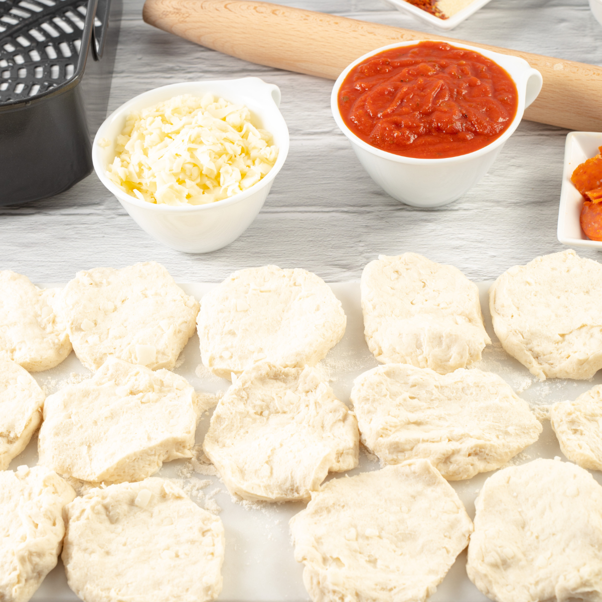 Rolling a canned biscuit flat with a rolling pin to make an air fryer pizza crust