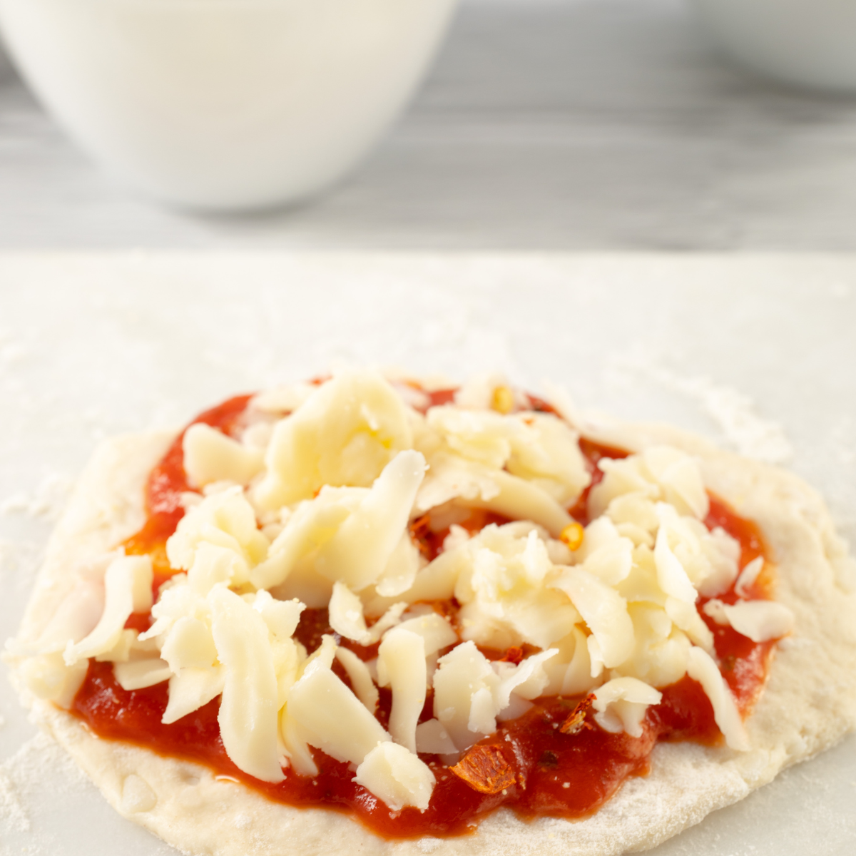 Flattened biscuit dough rounds pre-cooking in an air fryer basket