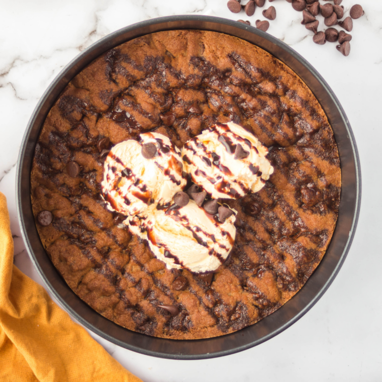 Air fryer chocolate chip cookie pizza sliced into wedges and topped with vanilla ice cream