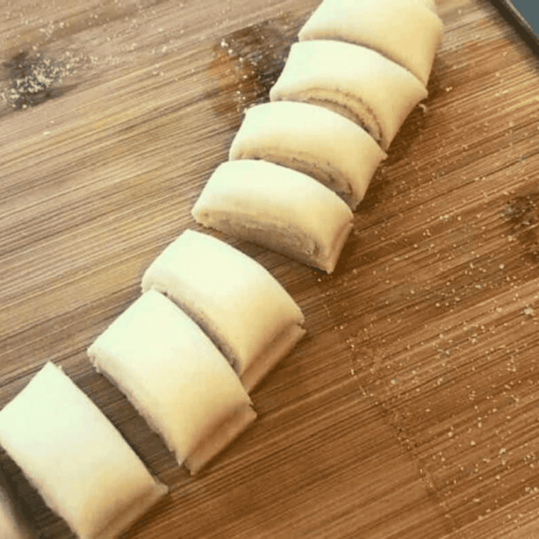 Brushing melted butter on dough, sprinkling cinnamon sugar, rolling, and slicing into ½-inch pieces.