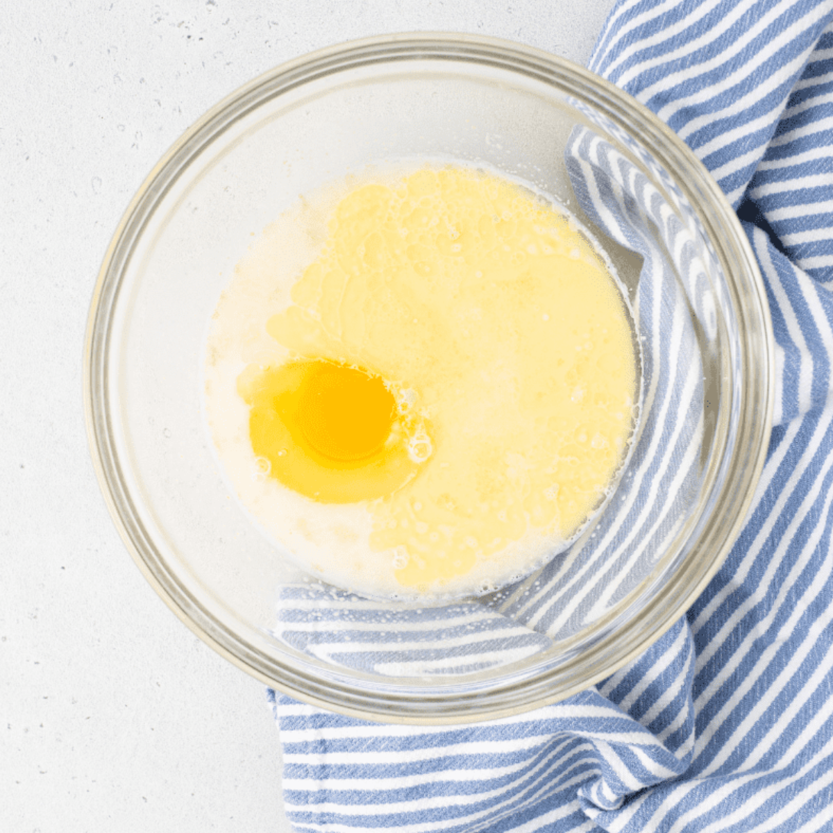 Warm milk, sugar, and yeast mixed in a measuring cup to activate for fluffy glazed donuts.