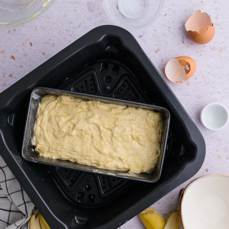 Air fryer with pound cake inside, baking at 320°F, checking doneness with toothpick