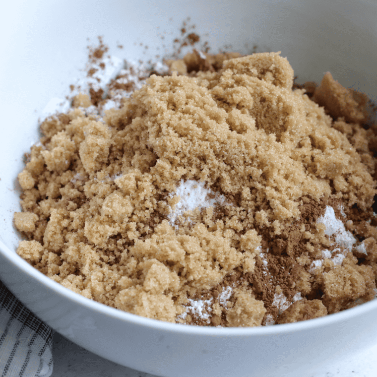 Mixing bowl with butter, brown sugar, and egg being combined for cookie dough.