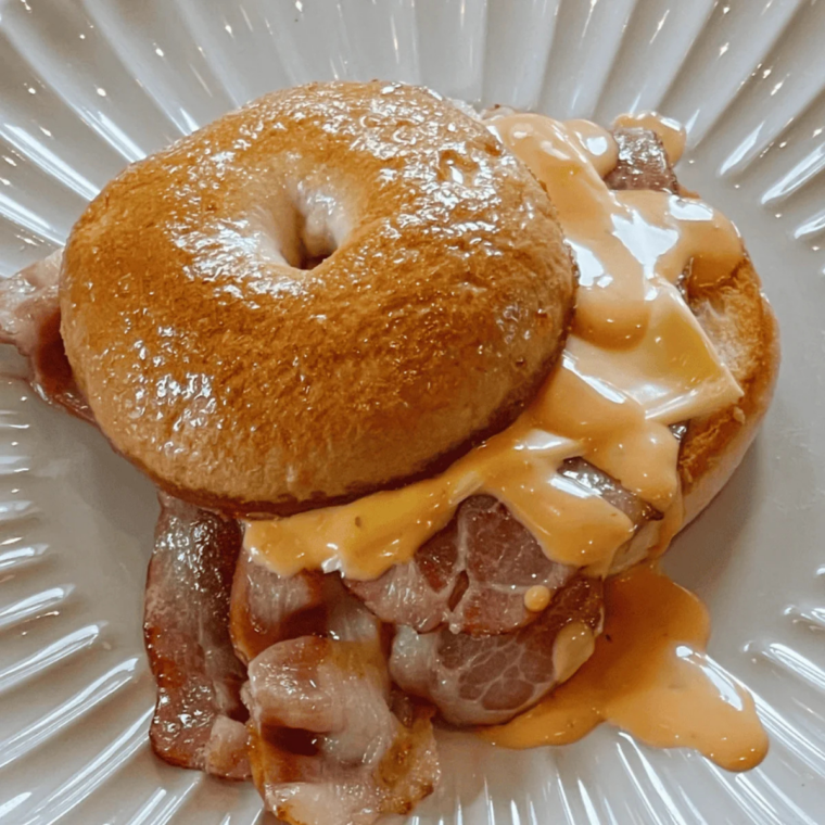 Easy Air Fryer Cheddar Cheese Bagels with no yeast, golden brown and topped with melted sharp cheddar cheese, served warm on a wooden board.