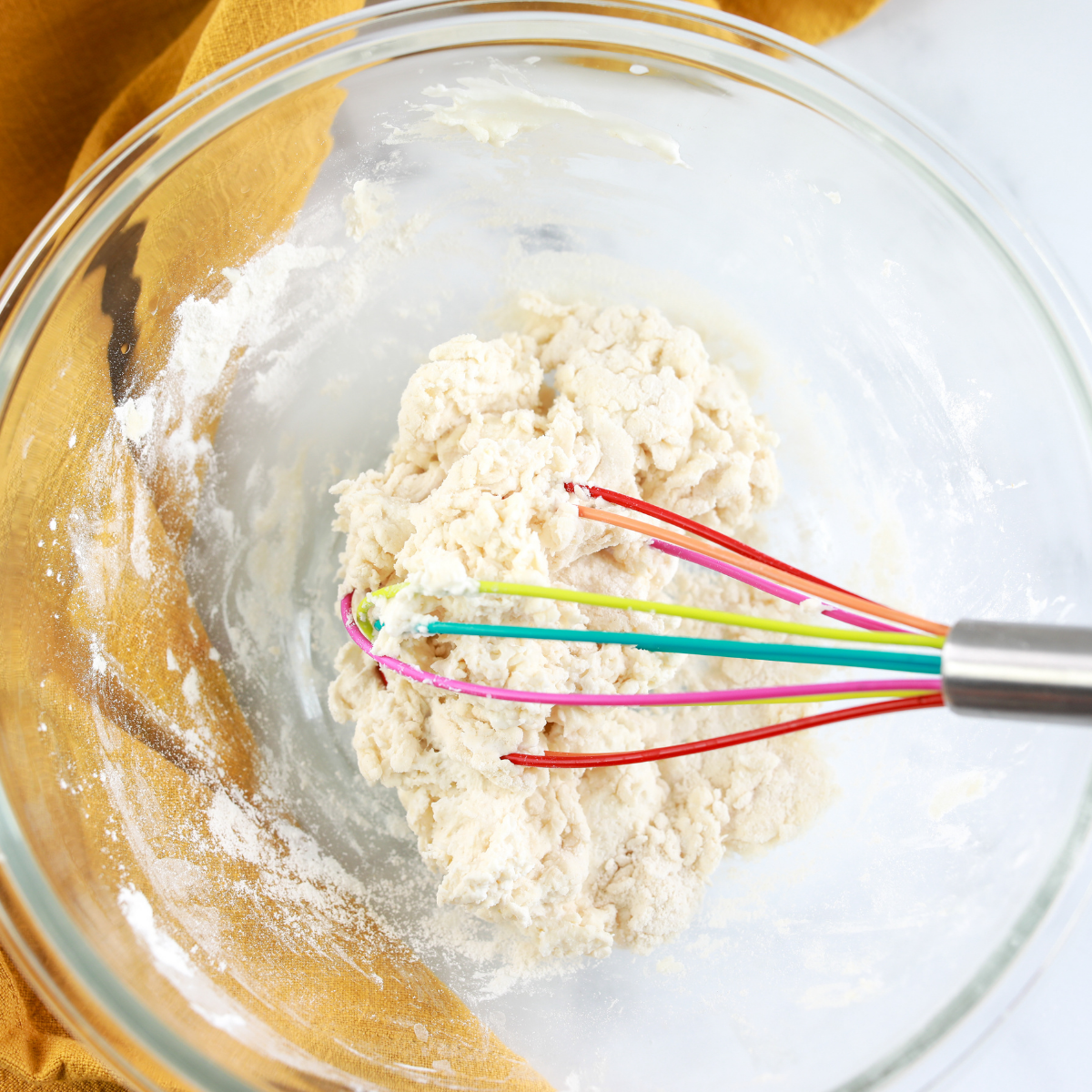 Stirring Greek yogurt, self-rising flour, and salt together in a glass mixing bowl to form a shaggy dough for Air Fryer Cheddar Cheese Bagels.