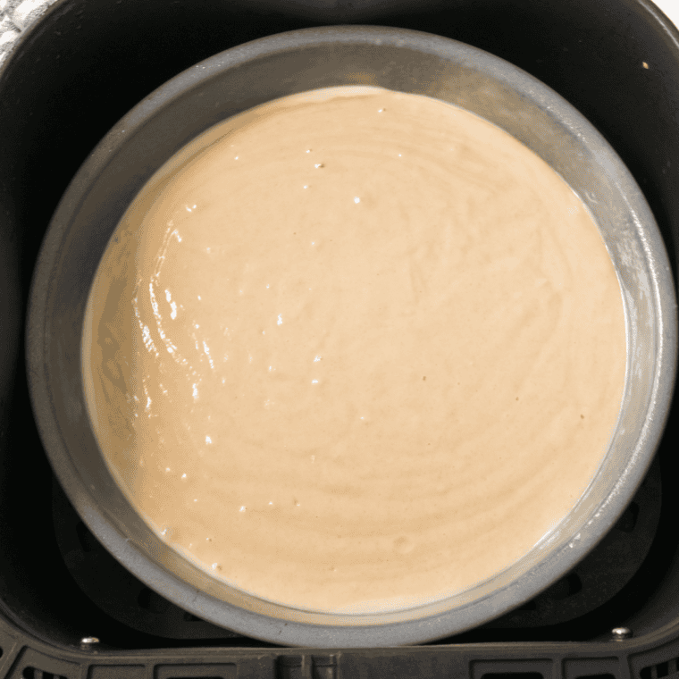 Crumb cake batter spread in a greased 7-inch cake pan for the air fryer