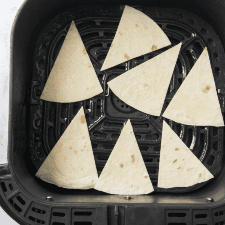 Air fryer basket filled with tortilla chips cooking at 375°F, being shaken halfway through for even crisping until golden and crunchy.