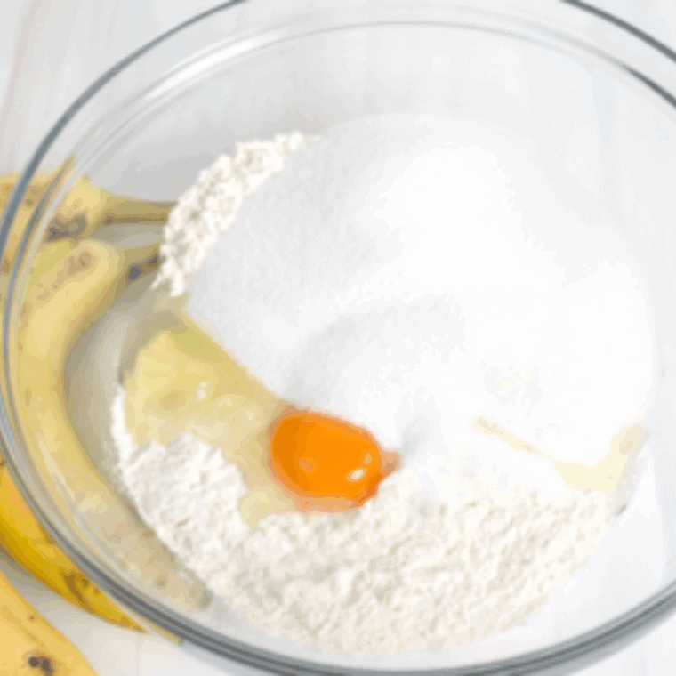Mashing ripe bananas with butter in a large mixing bowl until smooth