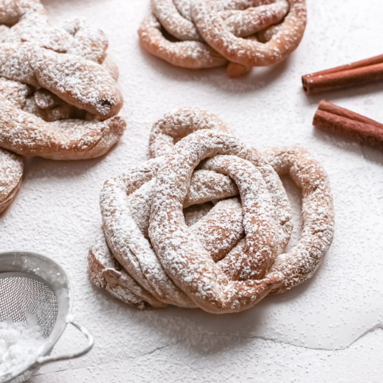 Air fryer funnel cakes topped with powdered sugar on a white serving plate