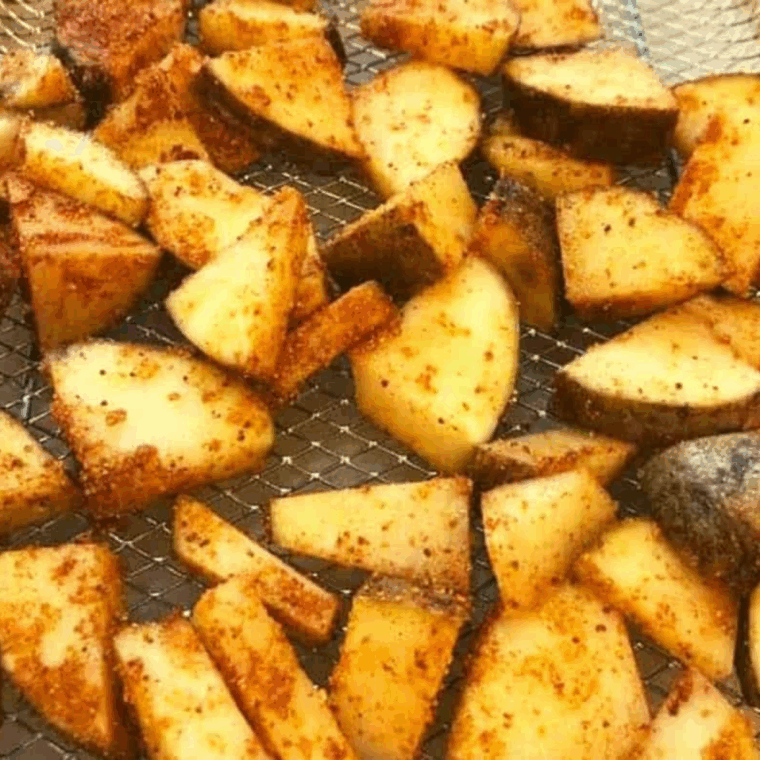 Golden air fryer potato cubes coated in glossy maple BBQ sauce, crispy outside, tender inside, served on a plate.