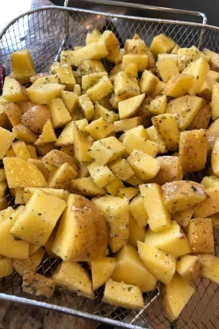 Cubed potatoes tossed with olive oil and dry ranch seasoning in a glass mixing bowl