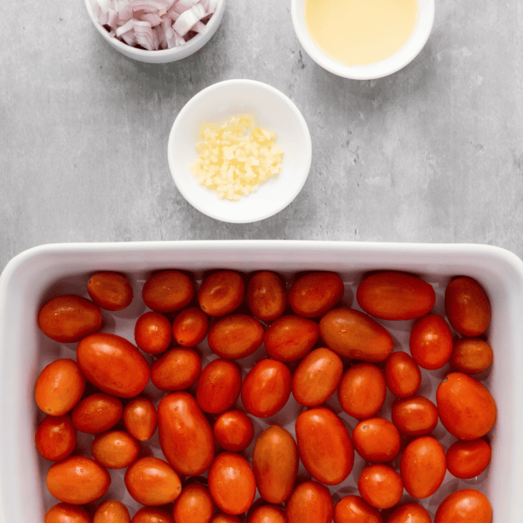 Cherry tomatoes, olive oil, salt, pepper, and Italian seasoning arranged on a marble counter