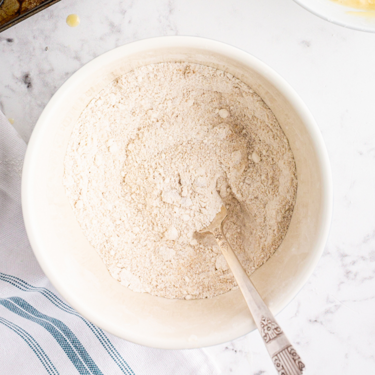 Flour and spices whisked together in a large white mixing bowl