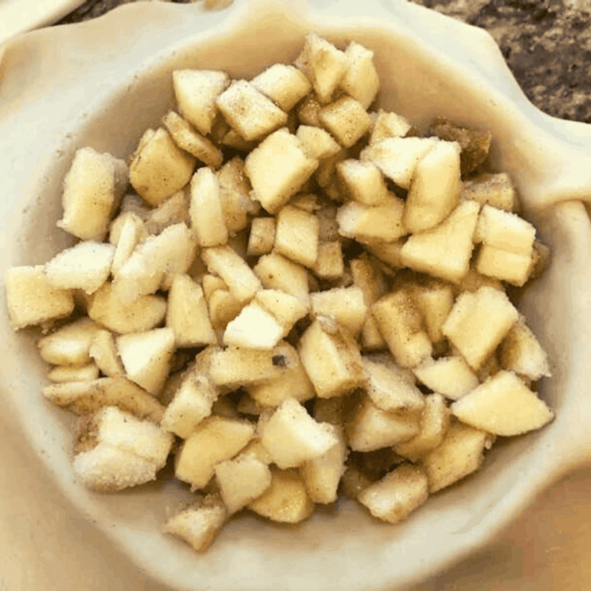 Apple filling poured into pie crust with top crust and slits for baking.